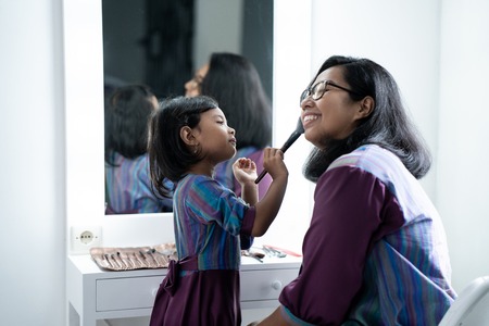 mother and daughter applying make up togetherの写真素材