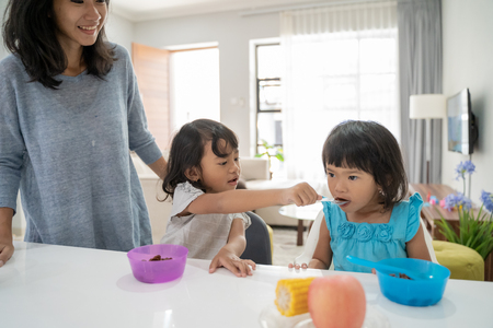 girl sister feeding each other while having breakfastの写真素材