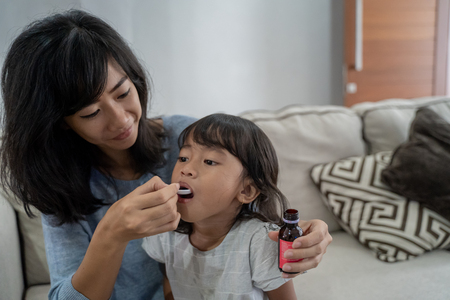 mother giving her daughter a medicineの写真素材