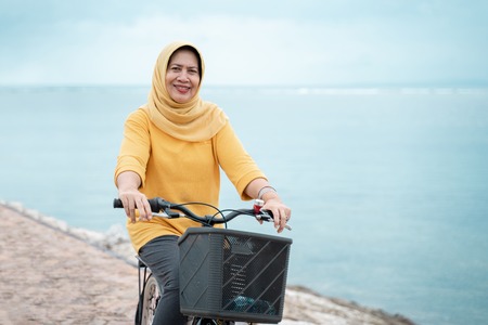 happy senior muslim female riding a bicycleの写真素材