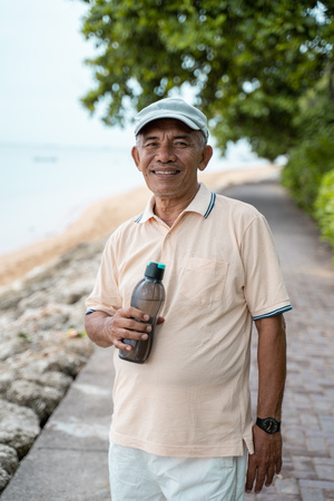 male senior asian smiling with water bottleの写真素材