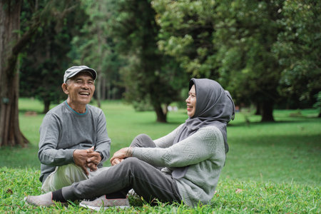 mature old man and woman sitting on a grass in the park