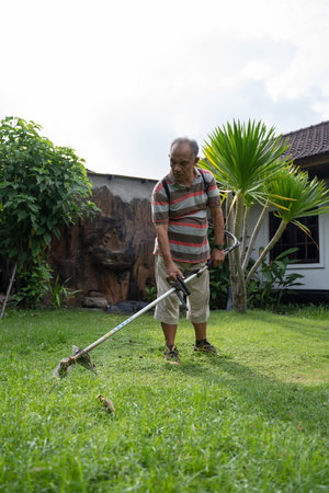 old asian man mowing his garden