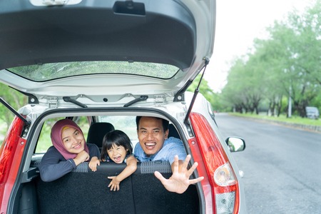 Muslim happy family smile and laugh in car, looks father hand waving goodbyeの写真素材