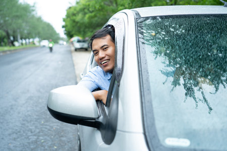 a man driver open the window and look out at the camera