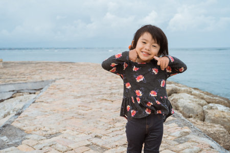 asian little girl pose with cute face smile when look at the camera on the beach