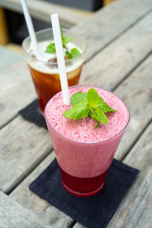 a pink strawberry smoothie with mint leaf on the wooden tableの写真素材