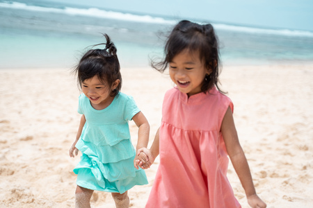 two little girl smile when playing together at the beachの写真素材