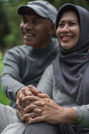 mature old man and woman sitting on a grass in the park