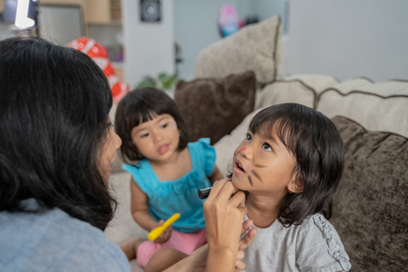 mom painting her kids in the faceの写真素材