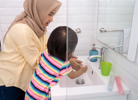 mom help her kid to wash her handsの写真素材