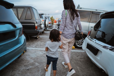 portrait of the mother holding her little daughter hand while walkingの写真素材