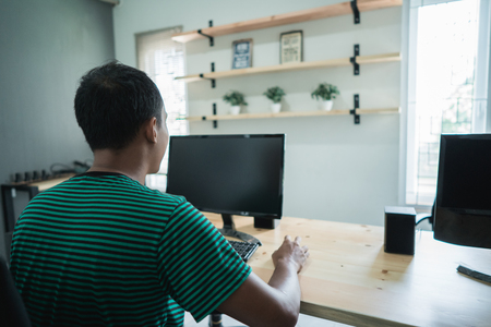 portrait of young worker sitting in front a monitor do the job with computerの写真素材