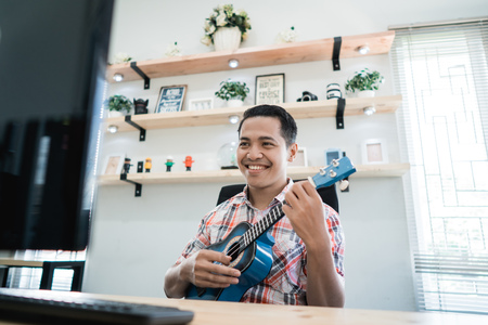 man playing guitar and smile in his officeの写真素材