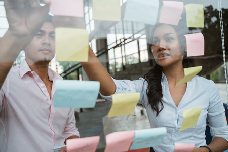 business partner brainstorming by sticking idea into the glass windowの写真素材