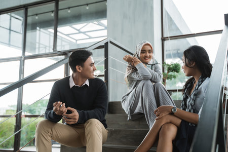 group of office friends chatting sit on the stairs when break