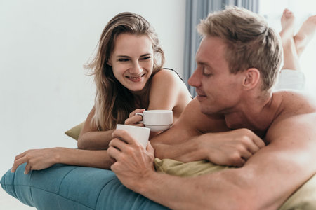 Couple lying on bed and having a cup of coffee