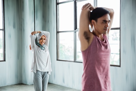 man sporty and hijab woman doing stretching before core exerciseの写真素材