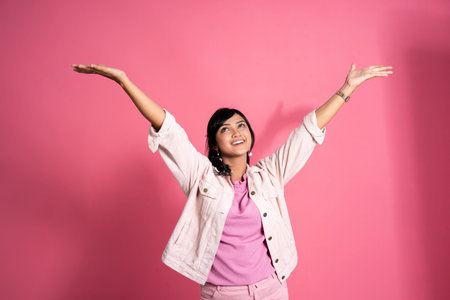 woman raised arm happily over pink background
