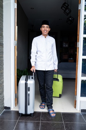 muslim man with head cap holding suitcaseの写真素材