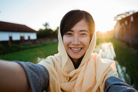 asian muslim woman take selfie with mobile phoneの写真素材