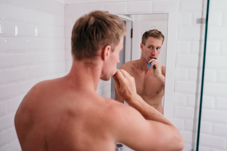 adult muscle man brushing his teeth in the bathroomの写真素材