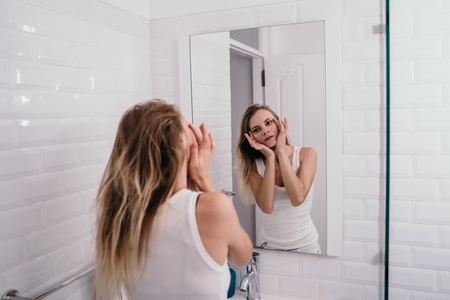 young woman reflected in the bathroom to see wrinklesの写真素材