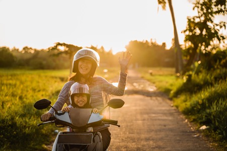 mother riding motorcycle with daughterの写真素材