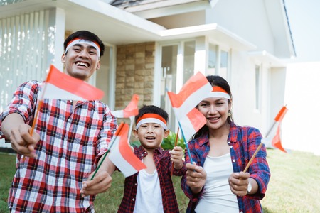 family holding a flag of indonesia. celebrating independenceの写真素材
