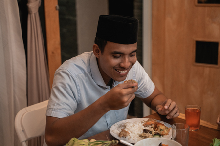 young muslim man eating dinner with familyの写真素材