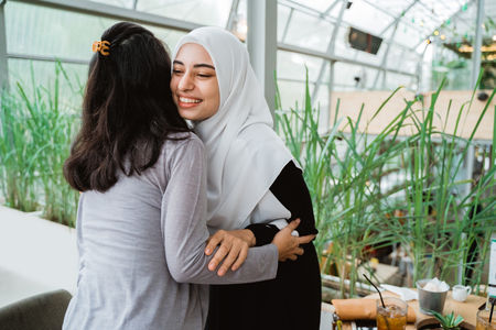 woman with scarf hugging and apologizingの写真素材