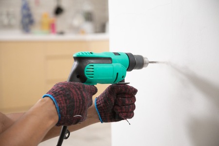 hands with gloves using electric drillの写真素材