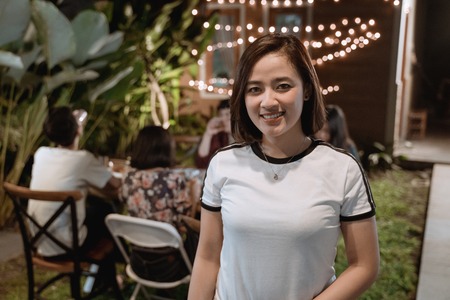 attractive asian woman smiling to camera while having dinner garden partyの写真素材