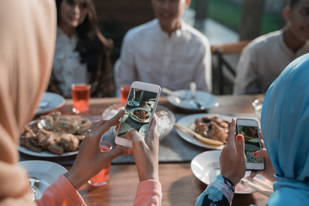 hijab women take photo of food dish while sitting on the house yardの写真素材