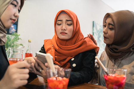 Hijab women and friends sad when reading bad newsの写真素材