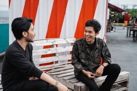 two friends chatting sitting on the wooden chairの写真素材