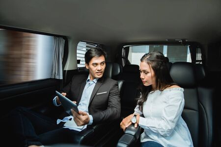 two business people meeting while sitting on passenger seat of carの写真素材