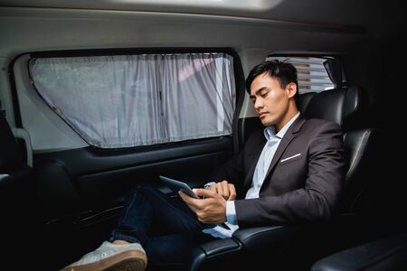 businessman with tablet sitting on passenger seatの写真素材