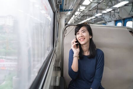 woman enjoying train trip or tram with her mobile phoneの写真素材