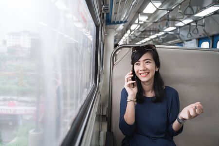 woman enjoying train trip or tram with her mobile phoneの写真素材