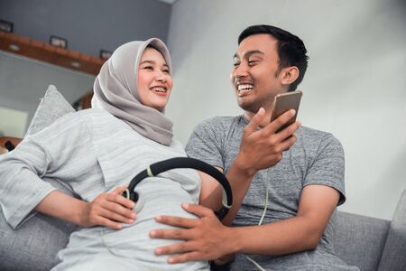 pregnant woman with headphone on her bellyの写真素材