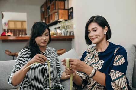 mother and daughter make a woven wrapper of ketupatの写真素材