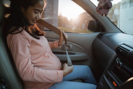 pregnant woman fasten her seatbelt while sitting on a carの写真素材