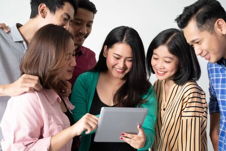 Asian women holding tablets with friendsの写真素材