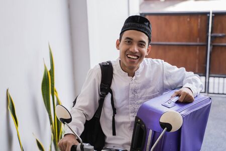 muslim man ride motorcycle for idul fitri    carrying suitcaseの写真素材
