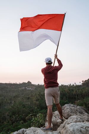 man with indonesian flag of indonesia on top of the mountainの写真素材