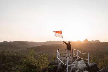 man with indonesian flag of indonesia on top of the mountainの写真素材