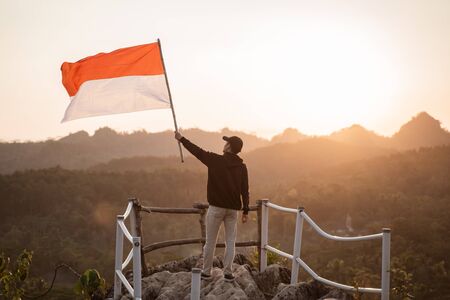 man with indonesian flag of indonesia on top of the mountainの写真素材