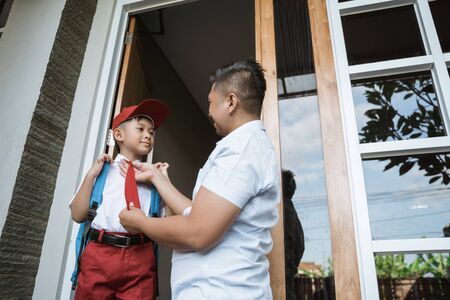 asian elementary student getting ready for school with fatherの写真素材