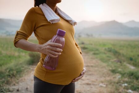 pregnant belly with bottle of water while exercisingの写真素材